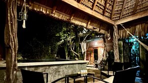 An outdoor seating area with chairs and a table, surrounded by a wooden structure with a thatched roof. - Private Room with A/C 400 m from Delfines Beach (Bajos de Chila)