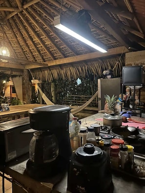 Eine Küche mit Strohdach, einer Kaffeemaschine und verschiedenen Küchenutensilien.