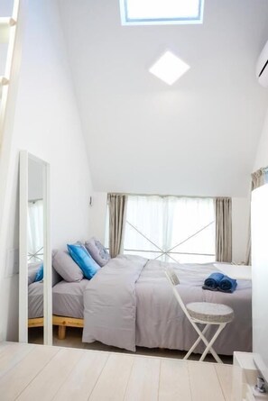 A bedroom with a bed, a small round table, a mirror, and a window with curtains. - Shukusei Shibuya (Shibuya)