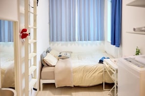 A bedroom with a bed, a desk, and a window with curtains. - Shukusei Shibuya (Shibuya)