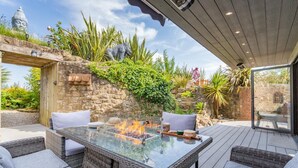 An outdoor patio with a glass-top table, wicker furniture, and a fire feature. - Luxury Jurassic Spa Retreat | Private Swim Spa, Hot Tub & Gated Grounds (co durham)