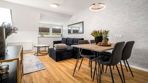A modern kitchen with a dining area, white brick walls, and a large window. - Liv OG Vacation Rental in Rechlin: with a garden, Wi-Fi, and private parking (Rechlin)