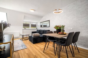 A modern kitchen with a dining area, white brick walls, and a large window. - Liv OG Vacation Rental in Rechlin: with a garden, Wi-Fi, and private parking (Rechlin)