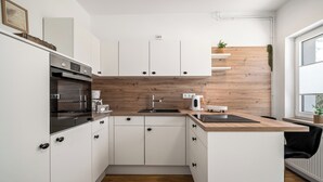 A modern kitchen with white cabinets, a wooden countertop, a built-in oven, and a sink. - Liv OG Vacation Rental in Rechlin: with a garden, Wi-Fi, and private parking (Rechlin)