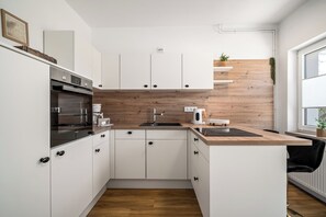 A modern kitchen with white cabinets, a wooden countertop, a built-in oven, and a sink. - Liv OG Vacation Rental in Rechlin: with a garden, Wi-Fi, and private parking (Rechlin)