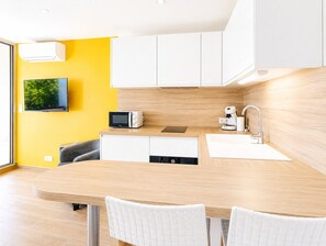 Eine moderne Küche mit Holzarbeitsplatte, weißen Schränken, einer integrierten Mikrowelle, einer Kaffeemaschine und einem Spülbecken.