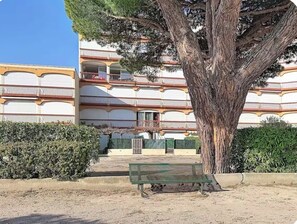Ein Gebäude mit mehreren Balkonen und einem Baum davor.
