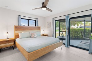 A bedroom with a bed, bedside tables, a ceiling fan, and a view through a glass door to an outdoor area. - 🏖️Sunshine Dock House | On Canal w/ Dock | Private Pool | Games 🏖️ (Fort Myers Beach)