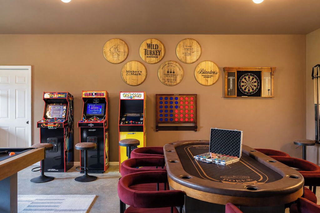 Ein Raum mit Billardtisch, Spielautomaten, Dartscheibe und Pokertisch.