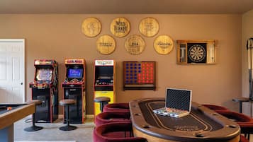 Ein Raum mit Billardtisch, Spielautomaten, Dartscheibe und Pokertisch.