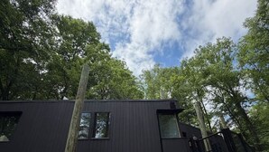 Una moderna cabina nera, sollevata su palafitte, in una foresta.