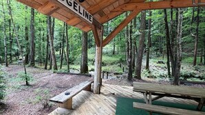 Un padiglione di legno con un cartello che riporta la scritta 'RIDGELINE', immerso in una foresta.