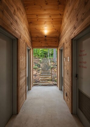Ein Holzbodenkorridor mit Teppichboden, der zu einer Steintreppe im Freien führt.