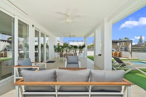 A modern outdoor seating area with a pool, glass doors, and ceiling fans. - Modern 3BR Villa w/ Pool & Cabana, Oranjestad (Oranjestad)