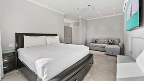 Een moderne slaapkamer met een groot bed, een sofa en een aan de muur bevestigde televisie.