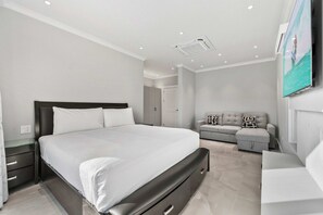 A modern bedroom with a large bed, a sofa, and a TV mounted on the wall. - Private Pool · BBQ · Gorgeous Views (Noord)