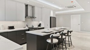 Een moderne keuken met een centraal eiland, barkrukken en inbouwapparatuur.