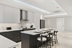 A modern kitchen with a central island, bar stools, and built-in appliances. - Private Pool · BBQ · Gorgeous Views (Noord)