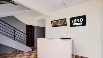 Eine Rezeption, eine Treppe und zwei Schilder mit den Aufschriften 'HOTEL' und 'OYO-Serviced' in einem Gebäude.