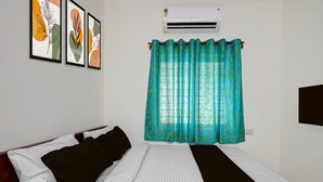 A room with a bed, air conditioning unit, curtains, and wall art. - Classic Seven Hills (Bengaluru)