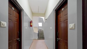 Ein Flur mit zwei Holztüren, einem Feuerlöscher und einer Treppe zu einer oberen Etage.