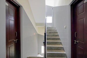 A staircase with a handrail, two wooden doors, and a small window at the top. - Classic Seven Hills (Bengaluru)