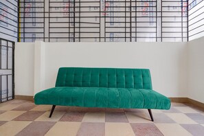Ein grünes Sofa in einem Raum mit einem gemusterten Boden und einer weißen Wand.