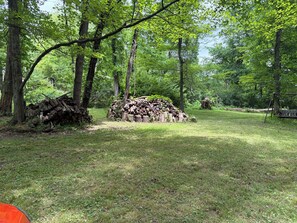 A forested area with a pile of logs and a swing set.