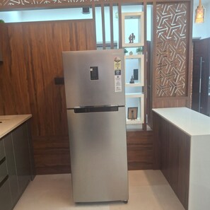 Una cocina moderna con refrigerador de acero inoxidable, armarios de madera y un panel decorativo en la pared.