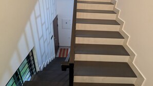 A staircase with a handrail, leading to a landing with a door and a light switch. - 5 Mins to Metro | 15 Mins to Airport – Perfect Launchpad for Explorers! (Aluva)