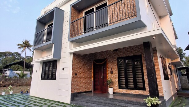 A two-story modern house with a balcony, a front door, and a small garden area. - 5 Mins to Metro | 15 Mins to Airport – Perfect Launchpad for Explorers! (Aluva)