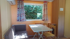 A small room with a window, a table, a chair, and a sofa.