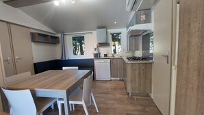 A compact kitchen with a dining area, a built-in dishwasher, and a stove.