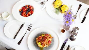 Una mesa dispuesta con platos de comida, cubiertos y un jarrón con flores.