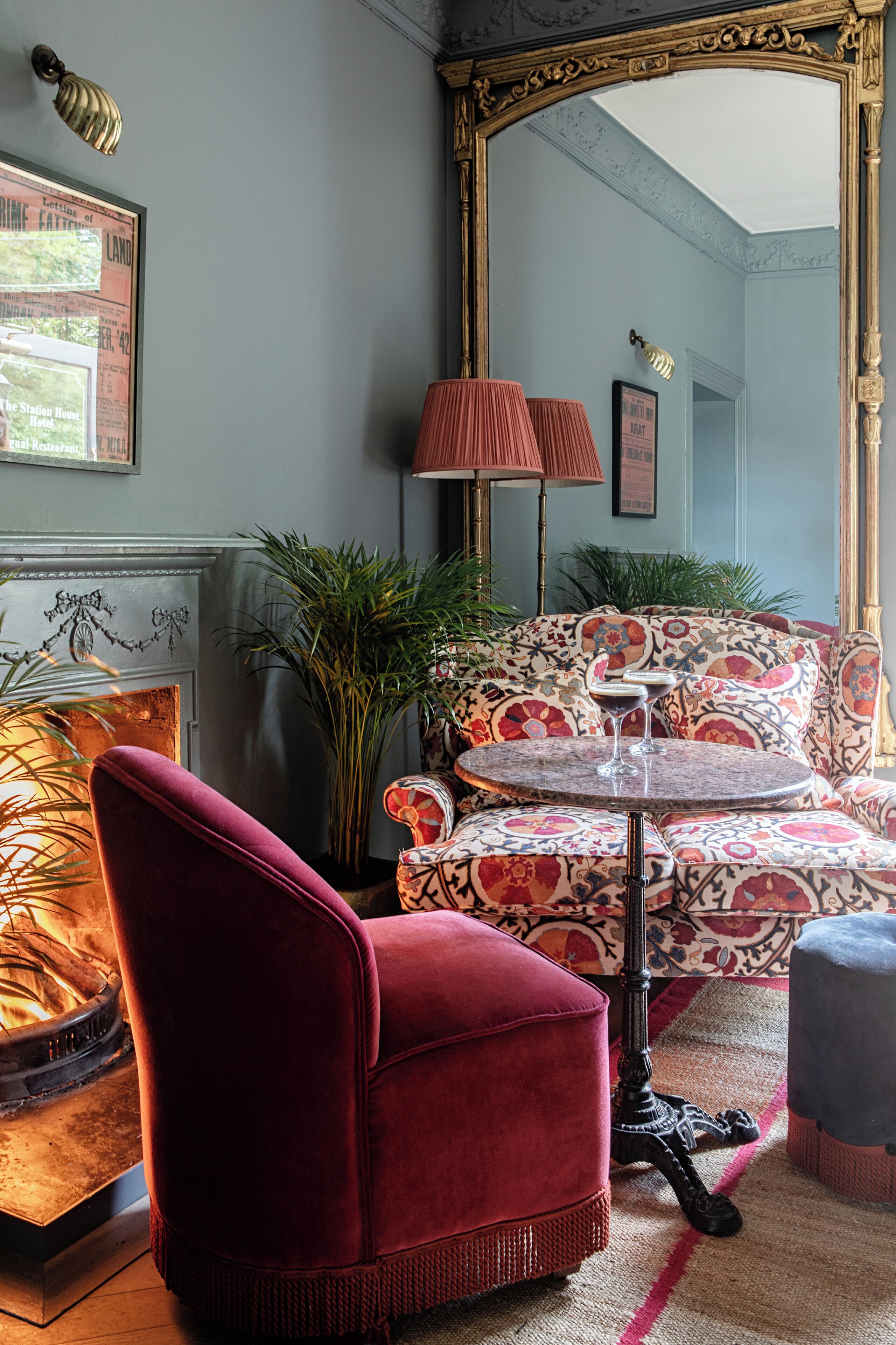 Een kamer met een rode fluweel fauteuil, een gestreept sofa en een ronde tafel met een martini glas.