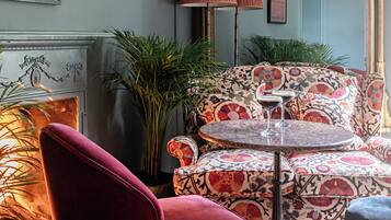 Een kamer met een rode fluweel fauteuil, een gestreept sofa en een ronde tafel met een martini glas.