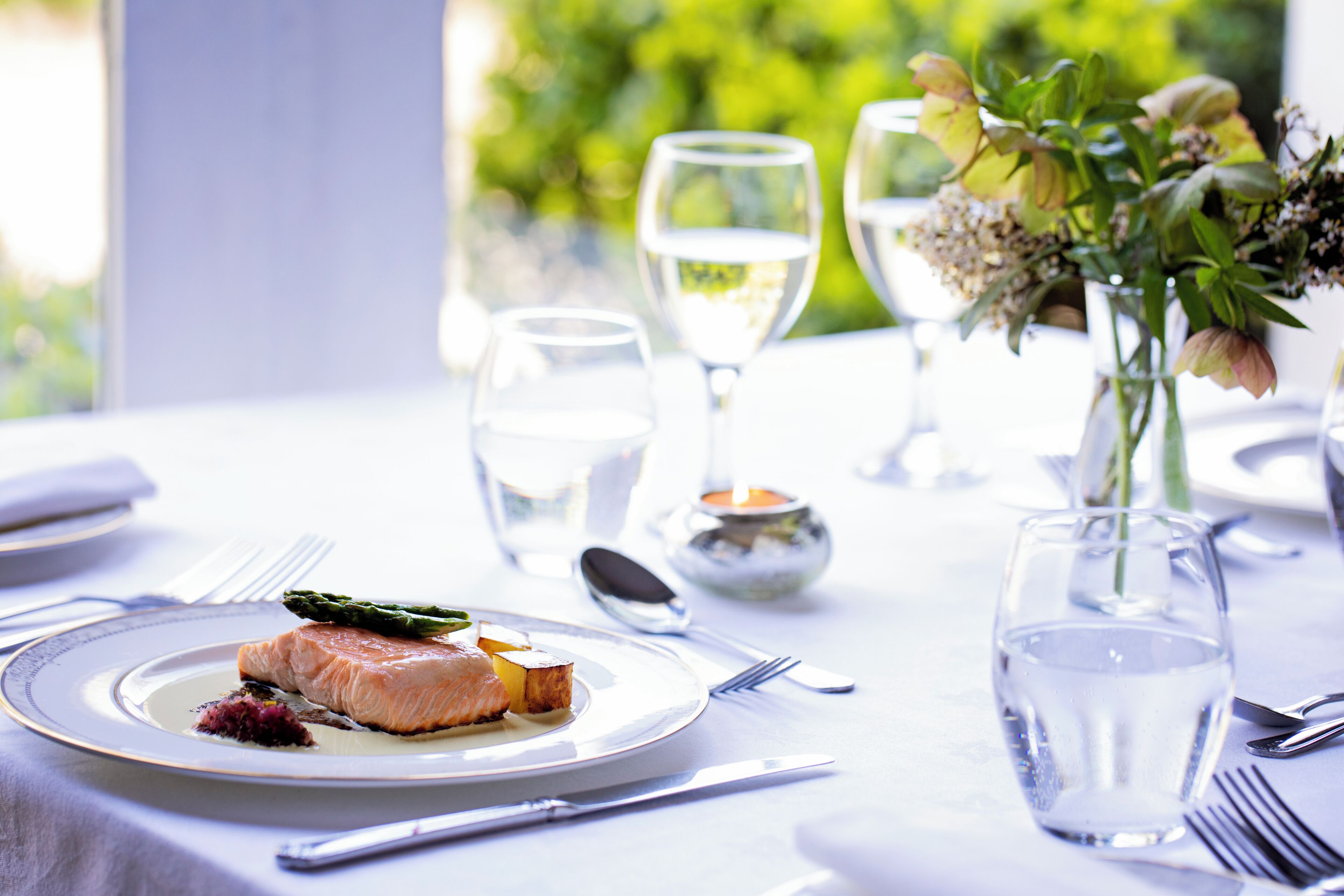 A dining table set with plates, cutlery, glasses, and a candle, suggesting a formal dining experience.