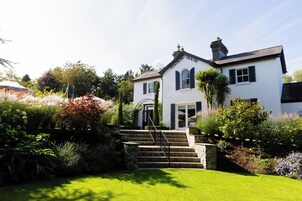 Un edificio blanco con un letrero que dice 'Station House', rodeado de abundante follaje y un jardín cuidado.