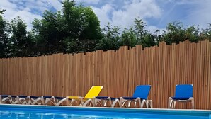 Una piscina con sillones de descanso.