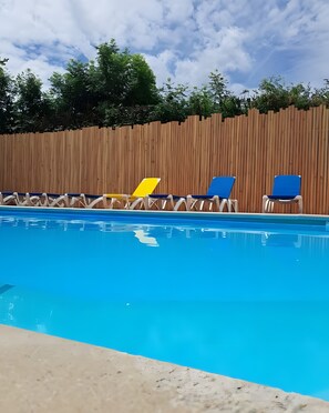 Una piscina con sillones de descanso.