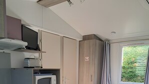 Cocina compacta con microondas, estufa y comedor para dos personas.