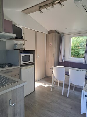 Cozinha compacta com micro-ondas, fogão e área de refeições com duas cadeiras.