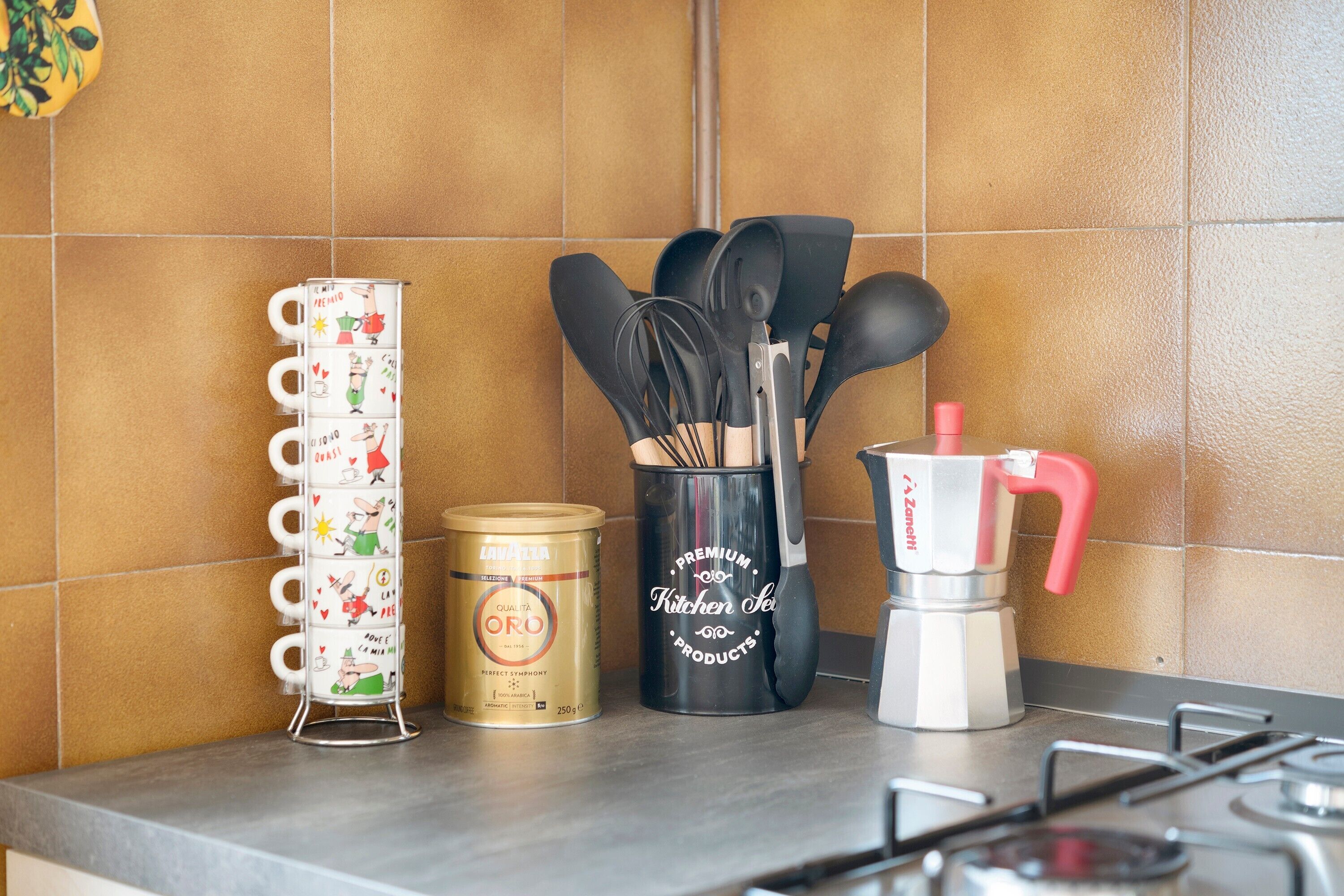 Eine Küchenarbeitsplatte mit einer Kaffeemaschine, einer Pastadose, einem Satz Schneebesen und einem Becherhalter.