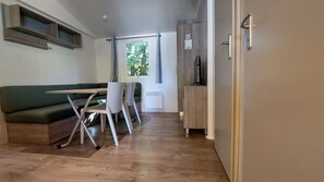 Un espace de vie compact comprenant un canapé, une table à manger, des chaises, un radiateur et une porte avec une poignée.