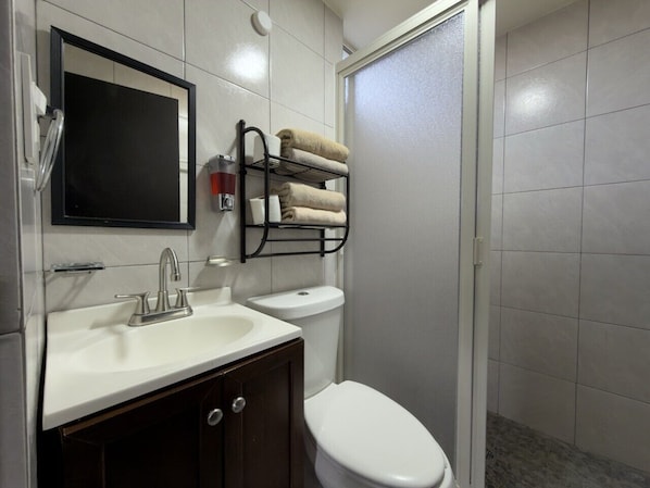Une salle de bain avec un lavabo blanc, des toilettes, un porte-serviettes avec des serviettes et un miroir.