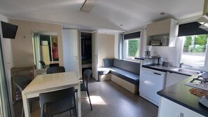 Cocina compacta con comedor, un banco integrado, microondas, lavamanos y ventana con vistas.