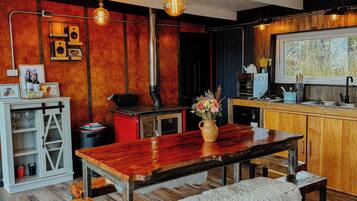 A modern kitchen with wooden cabinets, a large window, and a dining area with a wooden table and benches.
