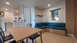 Un ambiente compatto con angolo cottura, un tavolo da pranzo con sedie, un divano e una finestra con vista.
