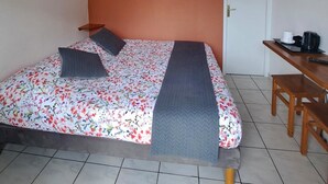 A room with a bed, a painting, a television, and a desk with a chair.