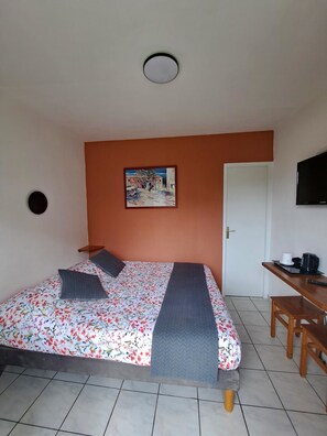 Une pièce comprenant un lit, un tableau, un téléviseur et un bureau avec une chaise.